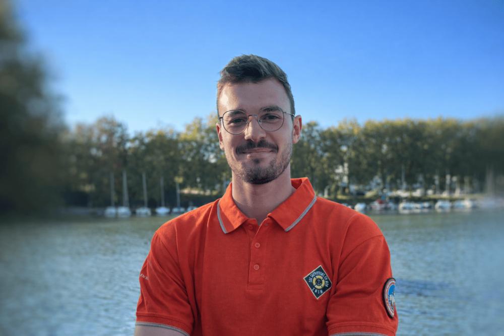 Un jeune homme, les bras croisés et souriant